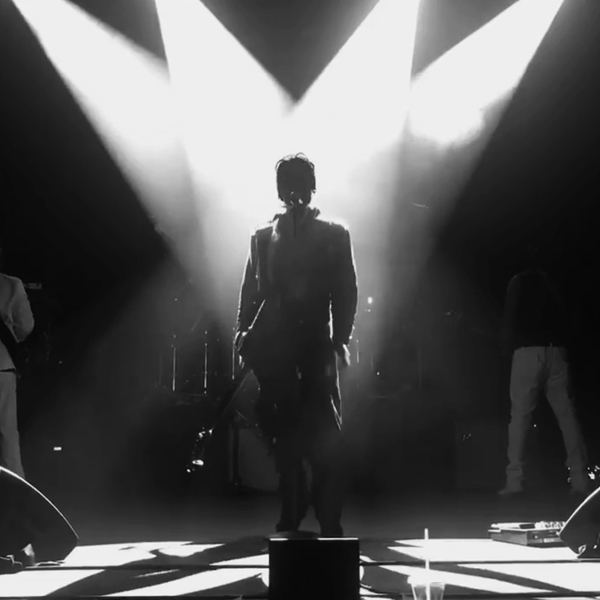 Silhouette of Marshall Charloff on stage lit by four spotlights.