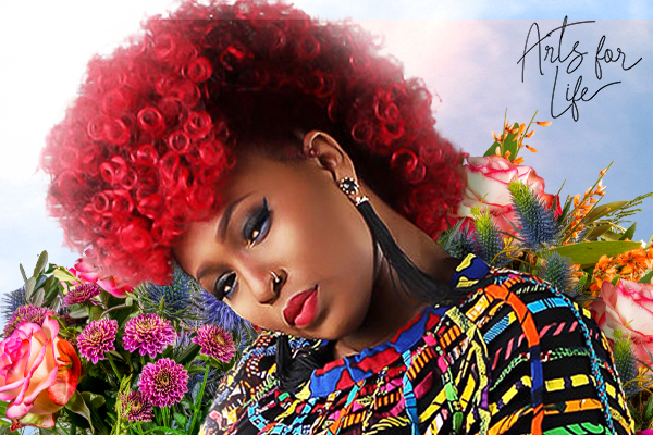Mumu Fresh with red hair and a colorful top tipping her head forward.