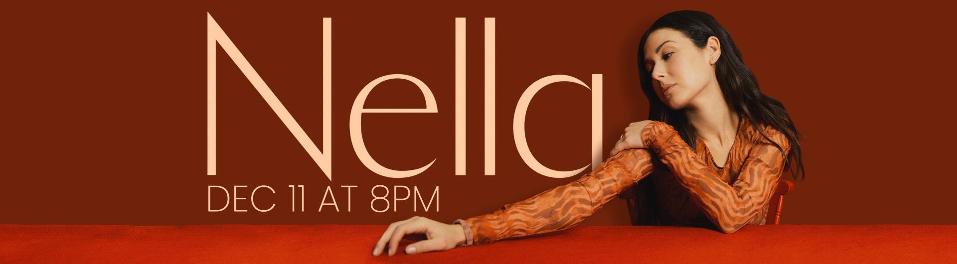 Nella looks to the side, one arm and hand outstretched atop a red surface, the background showing her name against a red background.