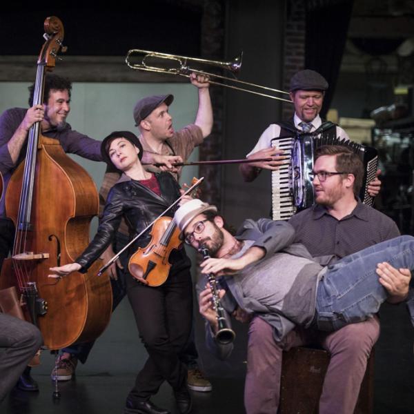 Members of Mostly Kosher in informal poses holding and playing their instruments.